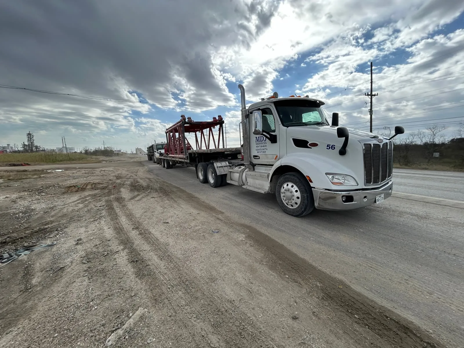 MDJ Services truck hauling red crane boom sections on a plant road in Southeast Texas