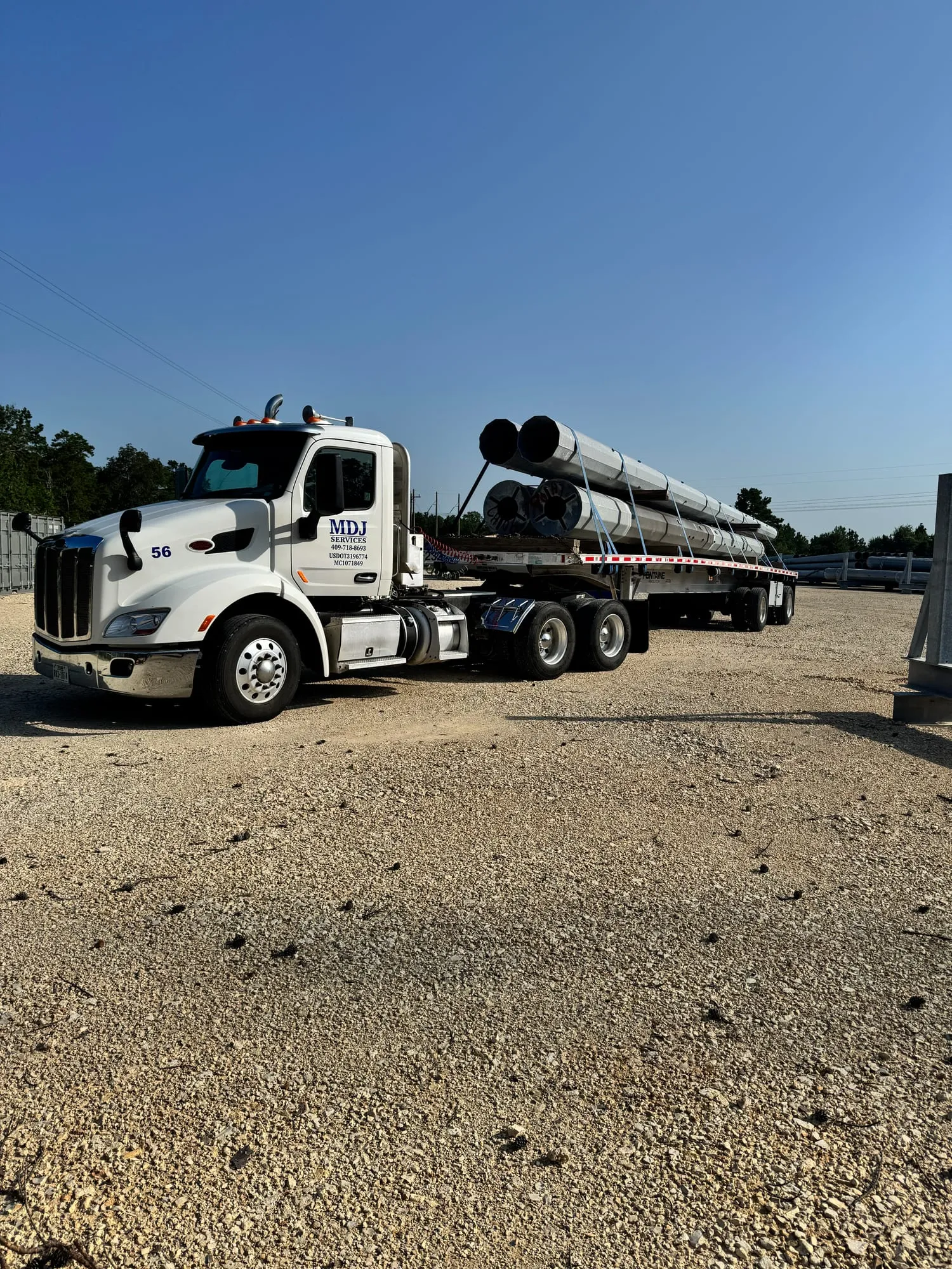 MDJ Services Truck 56 loaded with utility poles on a flatbed trailer in Southeast Texas